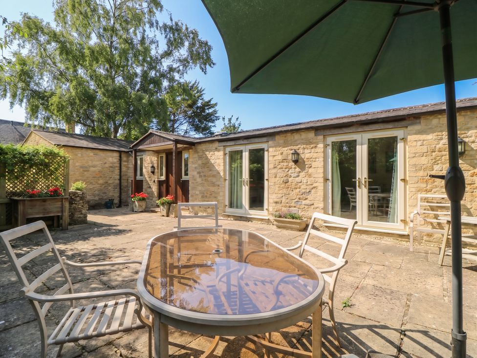 An outdoor dining area with a table and chairs at Meadow Lodge in Cerney Wick near South Cerney, Cotswolds