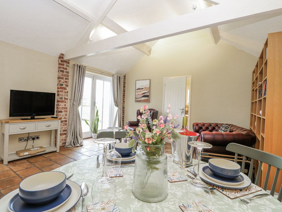 A living room with a television and dining table at Ivy Barn in Norwich