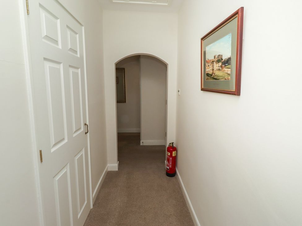 A hallway with a painting and fire extinguisher at Kittiwake at No 20 Seahouses