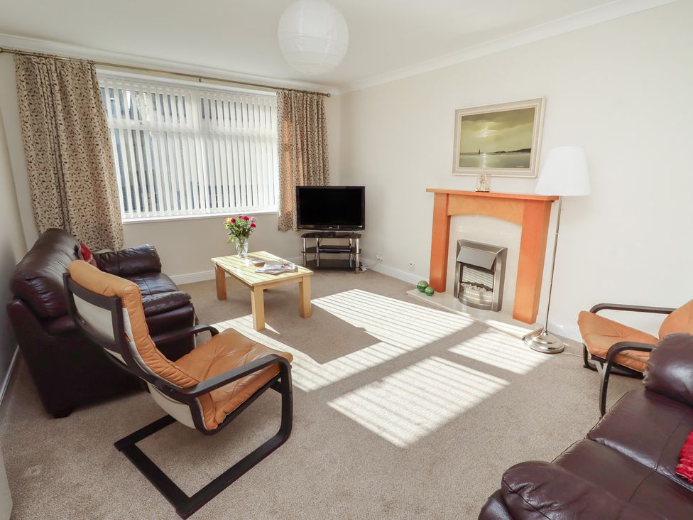 A living room with a television and seating arrangements at Kittiwake at No 20 in Seahouses