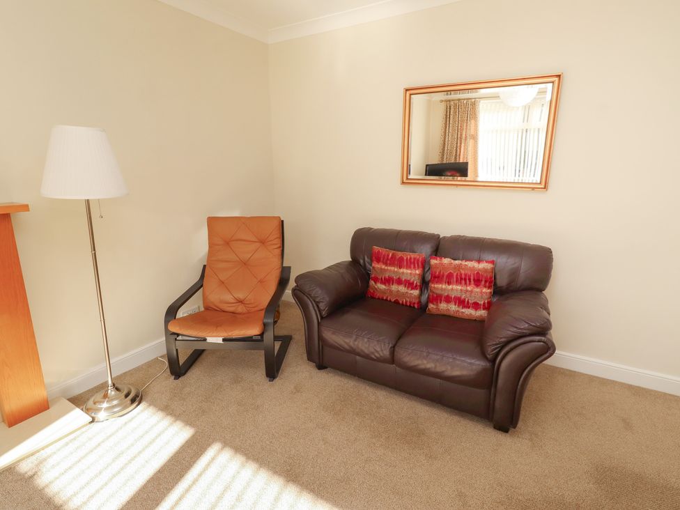 A living room with an armchair and couch at Kittiwake at No 20 Seahouses