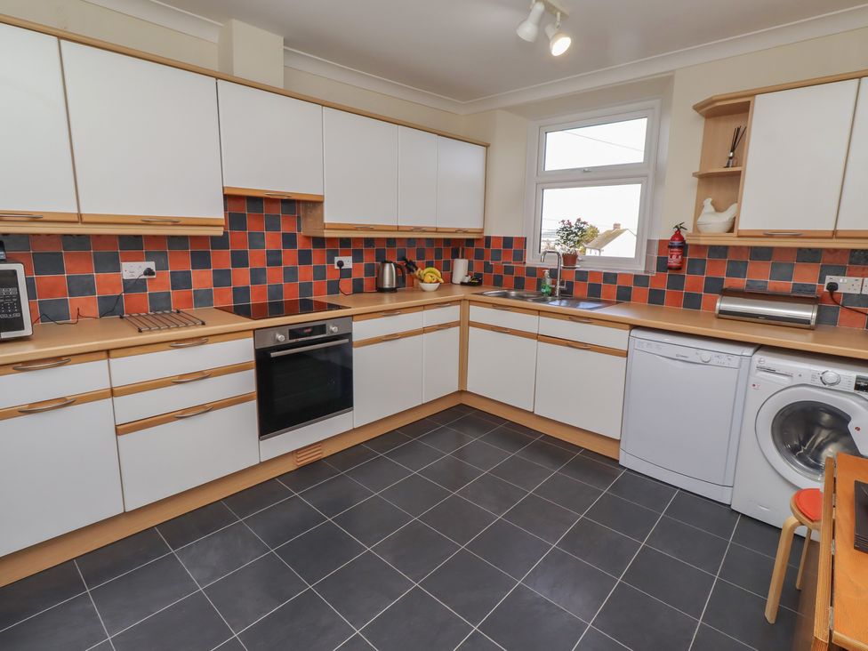 A kitchen with cabinets, oven, sink, and washing machine at Kittiwake at No 20 Seahouses