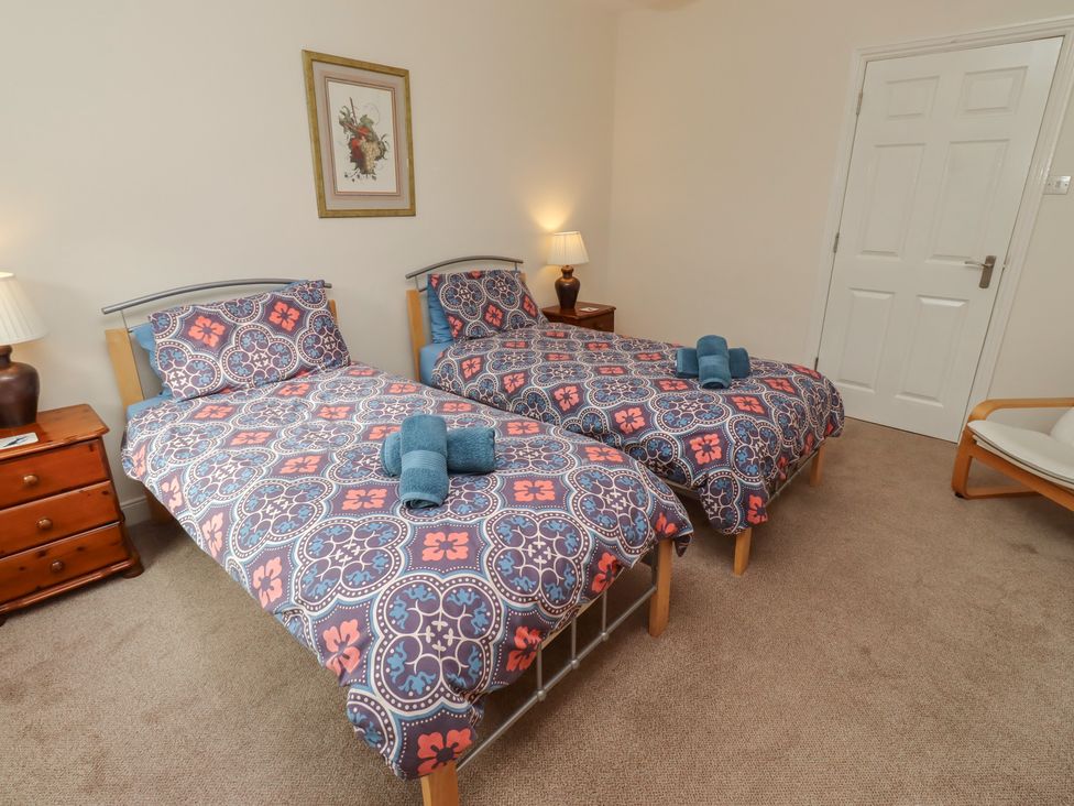 A bedroom with two single beds and a bedside table at Kittiwake at No 20 Seahouses