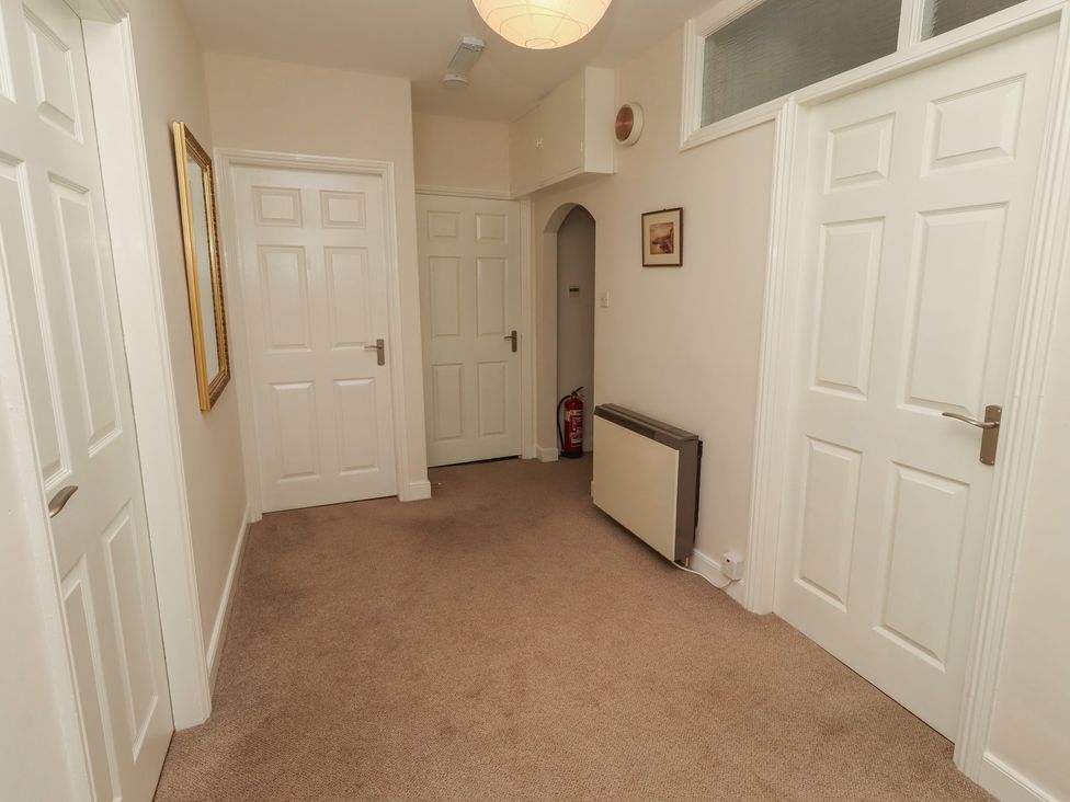 A hallway with multiple doors and a mirror at Kittiwake at No 20 Seahouses