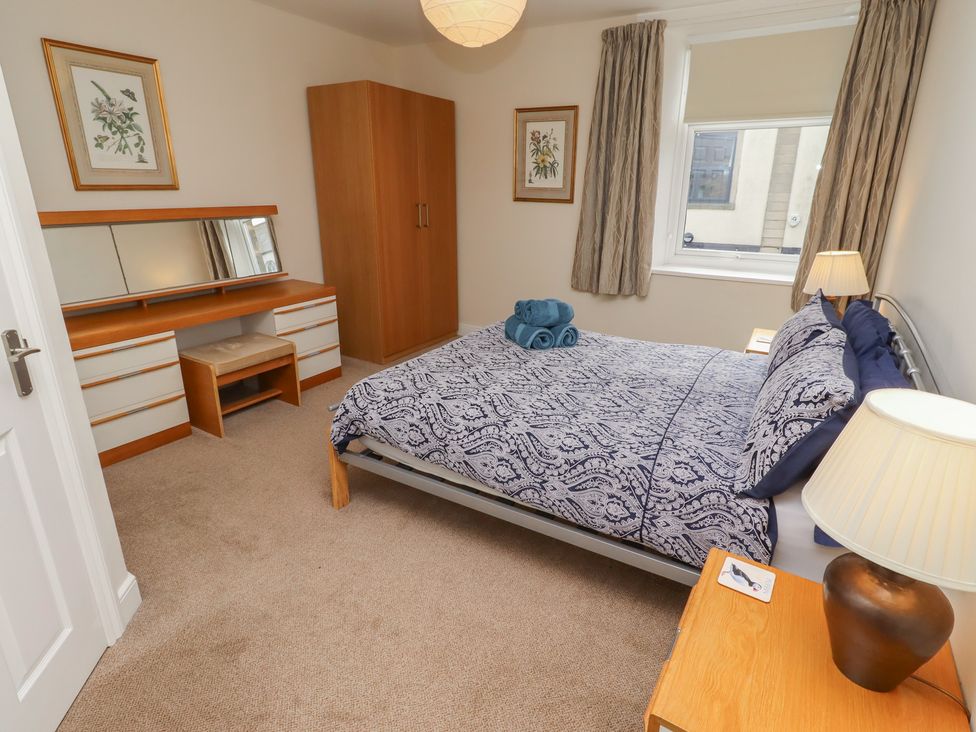 A bedroom with a bed, wardrobe, and dresser at Kittiwake at No 20 Seahouses