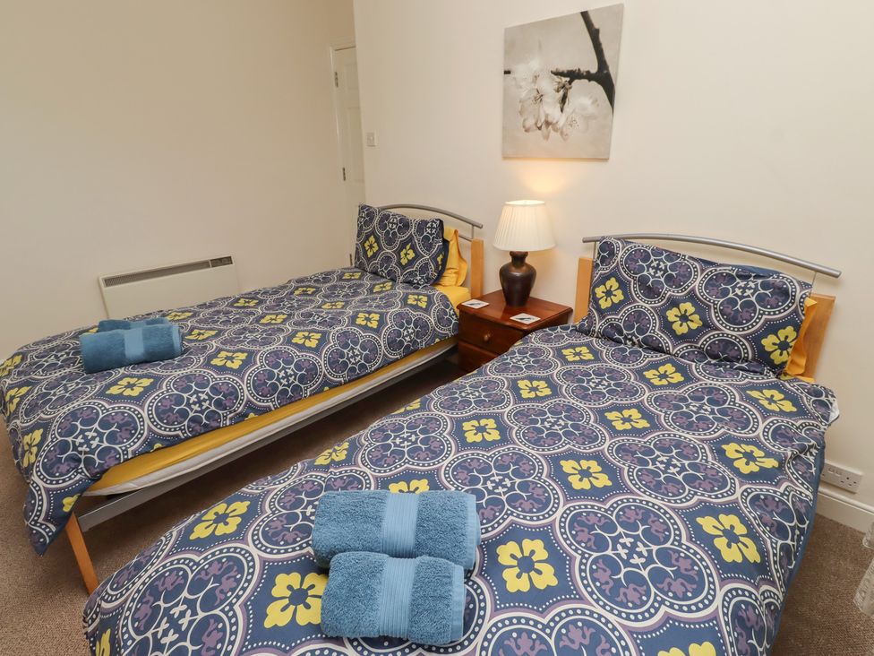 A bedroom with two beds and a bedside table at Kittiwake at No 20 Seahouses