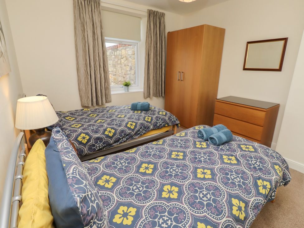 A bedroom with two beds and a wardrobe at Kittiwake at No 20 Seahouses