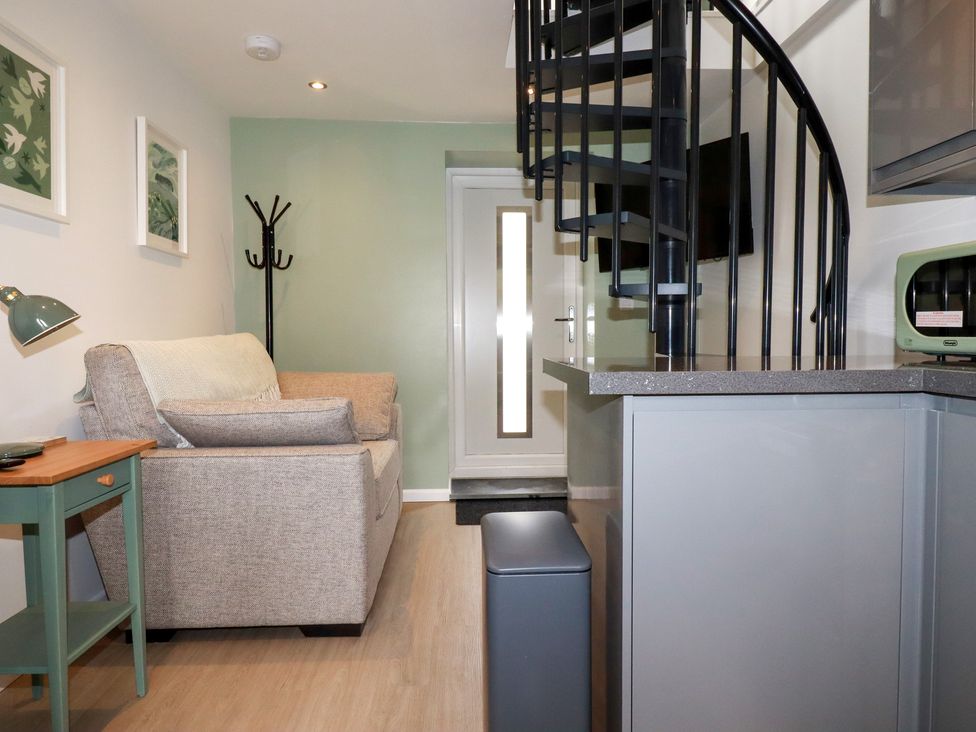 A living room with a sofa and spiral staircase at The Annex At The Barn in Pelynt