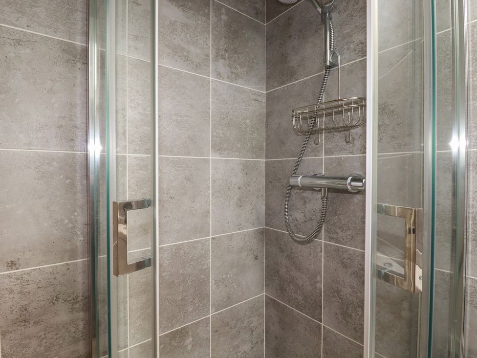A shower enclosure with wall tiles and fittings at The Annex At The Barn in Pelynt