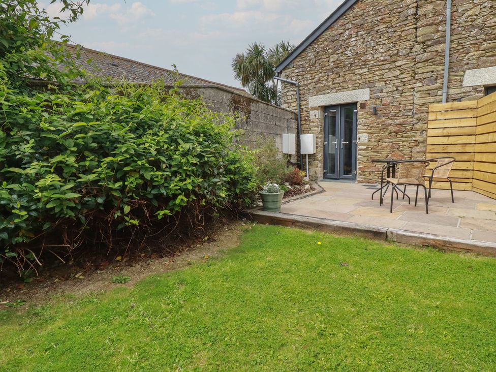 A garden with a paved patio and chairs at The Annex At The Barn in Pelynt