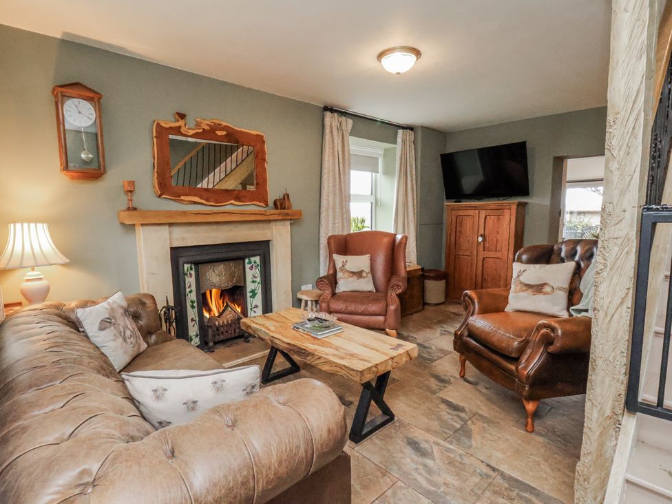 A living room with a sofa, table and fireplace at Ingleside Cottage in Whitby