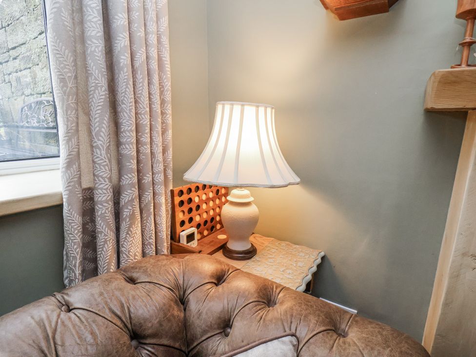 A lamp on a table beside a curtain in a living room at Ingleside Cottage in Whitby