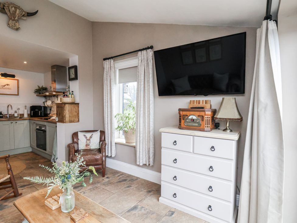 A living room with a television and a dresser at Ingleside Cottage in Whitby
