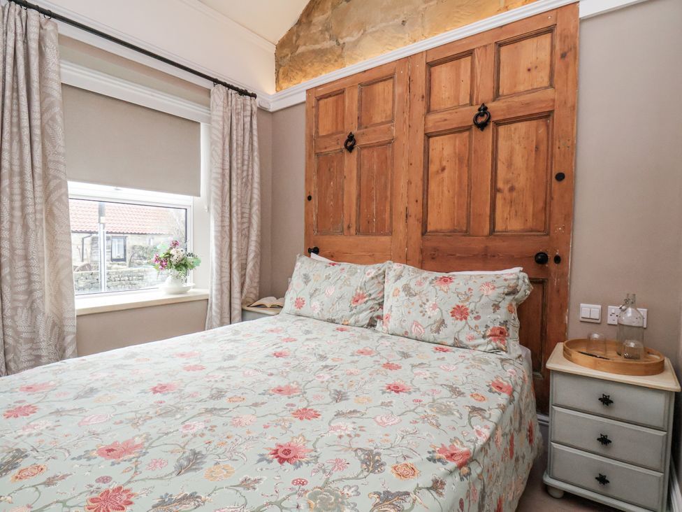 A bedroom with a bed and wooden doors at Ingleside Cottage in Whitby