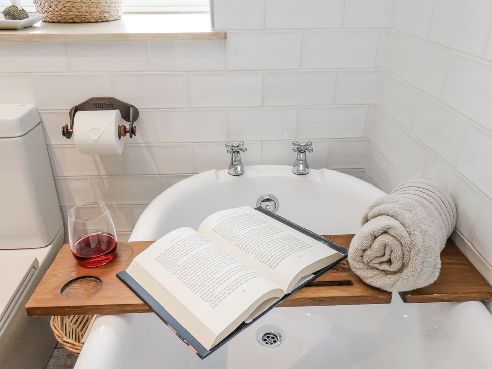 A bathtub with a book and wine glass at Ingleside Cottage in Whitby