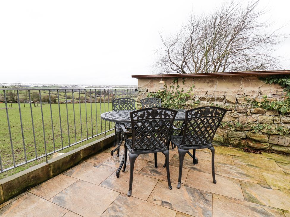 A table and chairs on a patio overlooking grass at Ingleside Cottage in Whitby