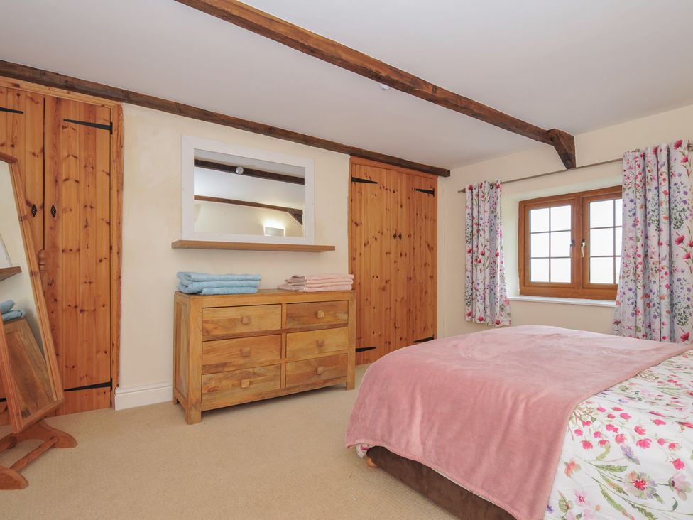 A bedroom with a bed, dresser, and curtains at Little Blagdon Beaworthy