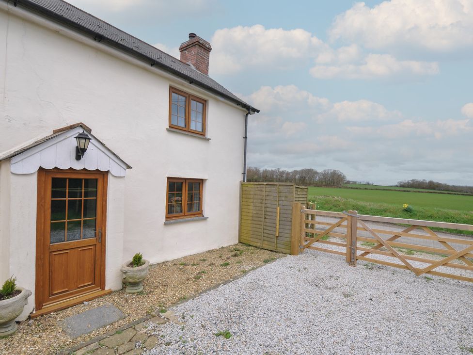 A cottage exterior with a gate and gravel driveway at Little Blagdon in Ashwater