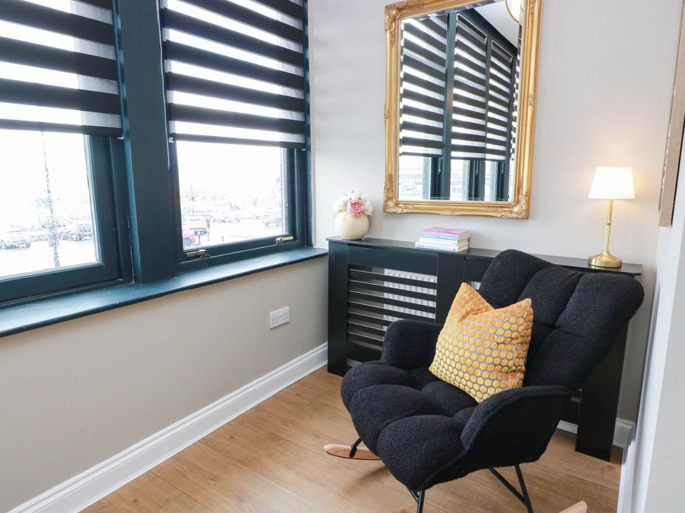 A snug with a chair, lamp, mirror, and window at Flat 1 86 Gallowgate Street in Largs