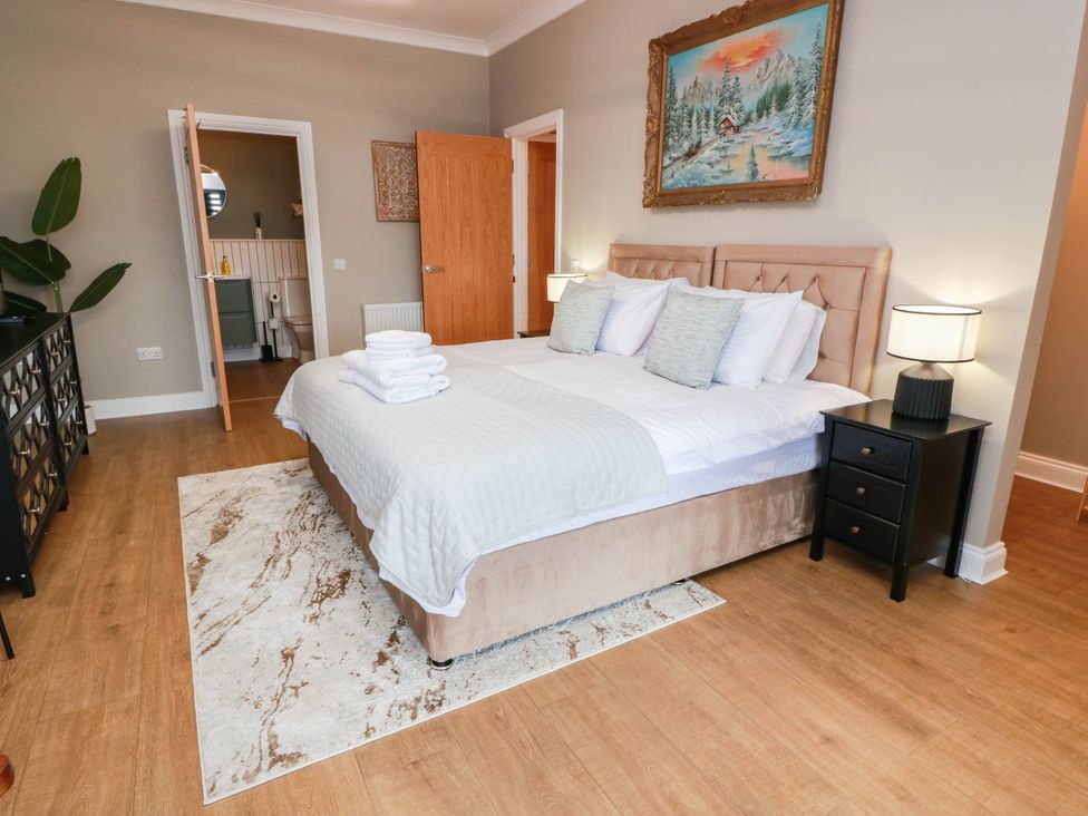 A bedroom with a bed, bedside tables, and a painting at Flat 1 86 Gallowgate Street in Largs