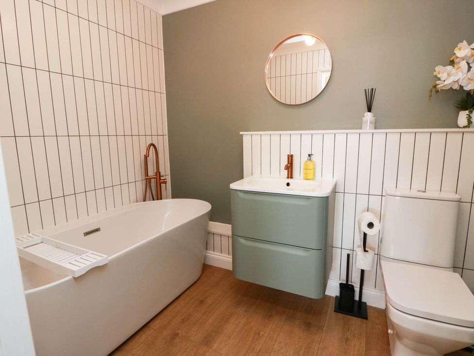 A bathroom with a bathtub, vanity, mirror, and toilet at Flat 1 86 Gallowgate Street Largs