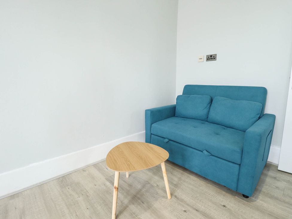 A living room with a blue sofa and a wooden table at The Ocean House   --- Sea Whisper (Top Floor )  Le Strange Terrace in Hunstanton