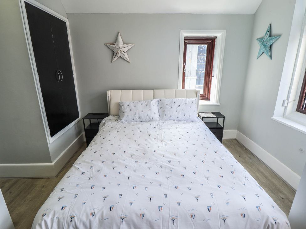 A bedroom with a bed and two windows at The Ocean House   --- Sea Whisper (Top Floor )  Le Strange Terrace, Hunstanton