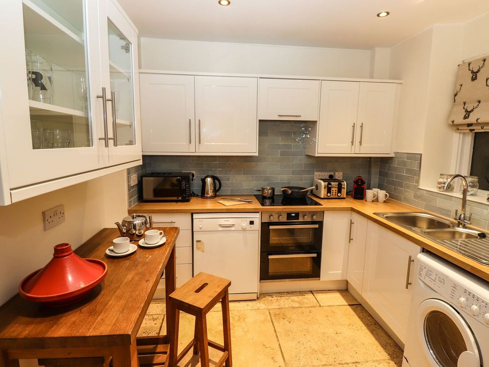 A kitchen with appliances and a table at Waterhead Cottage Ambleside