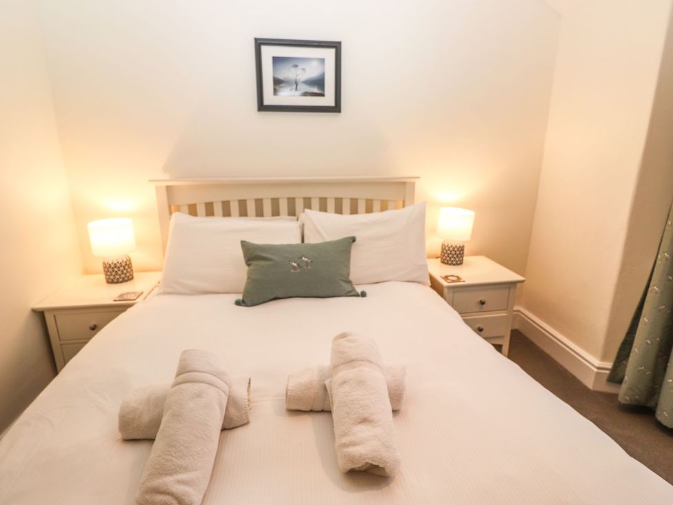 A bedroom with a bed and towels arranged at Waterhead Cottage in Ambleside