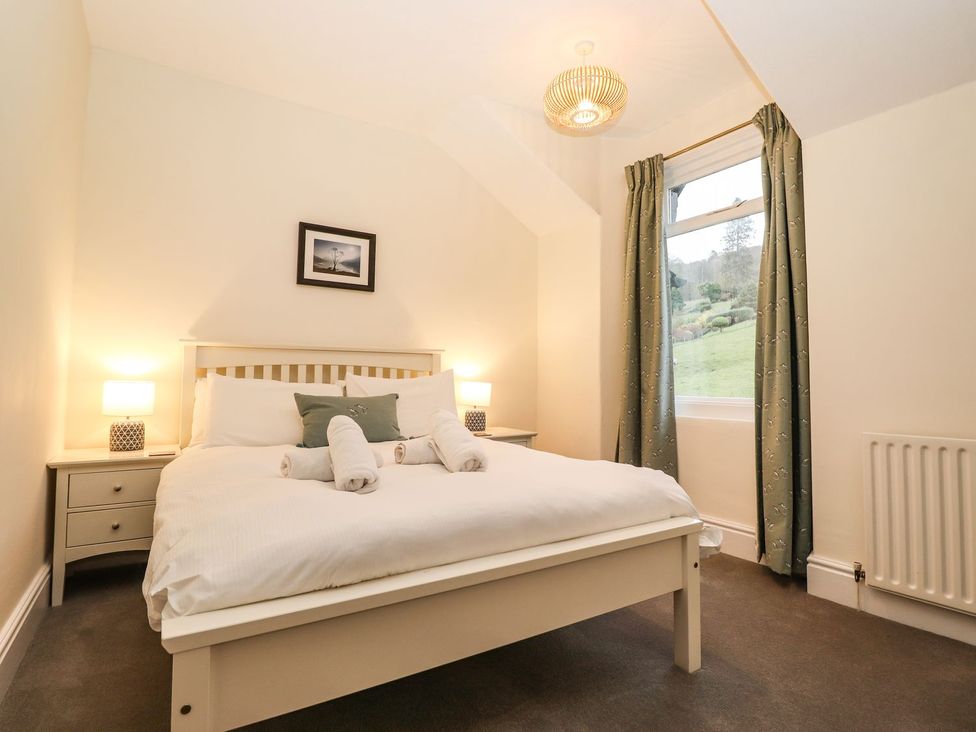 A bedroom with a bed, bedside tables and a window at Waterhead Cottage in Ambleside
