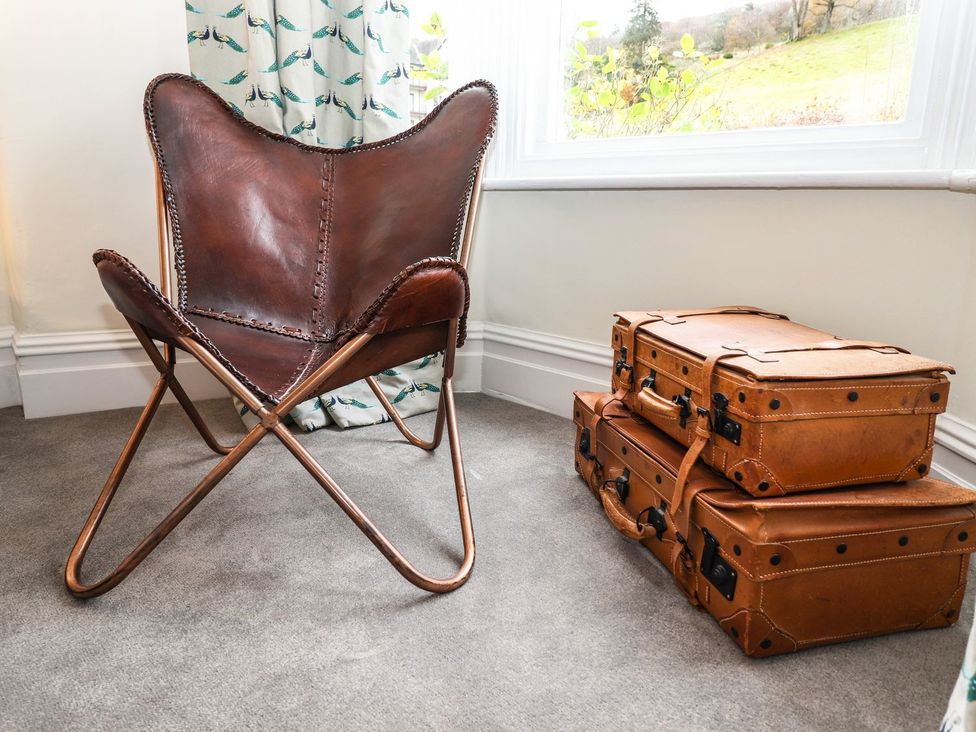 A chair and suitcases near a window at Waterhead Cottage in Ambleside