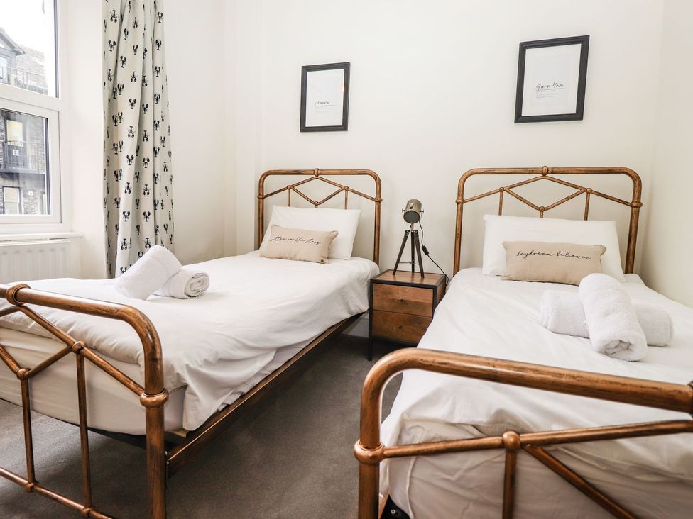 A bedroom with two single beds and a nightstand at Waterhead Cottage in Ambleside