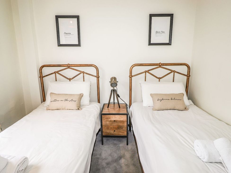 A bedroom with two beds and a nightstand at Waterhead Cottage Ambleside