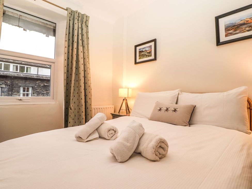 A bedroom with a bed, pillows, and a lamp at Waterhead Cottage in Ambleside