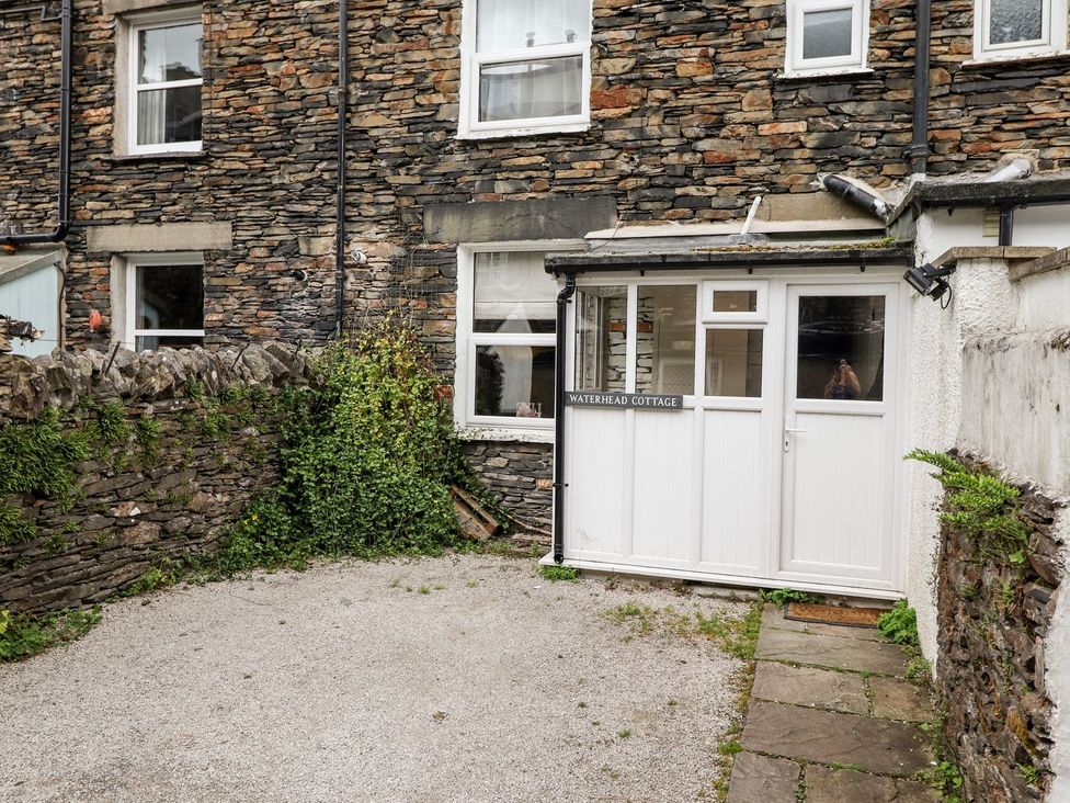 An outdoor area with a stone wall and cottage entrance at Waterhead Cottage in Ambleside