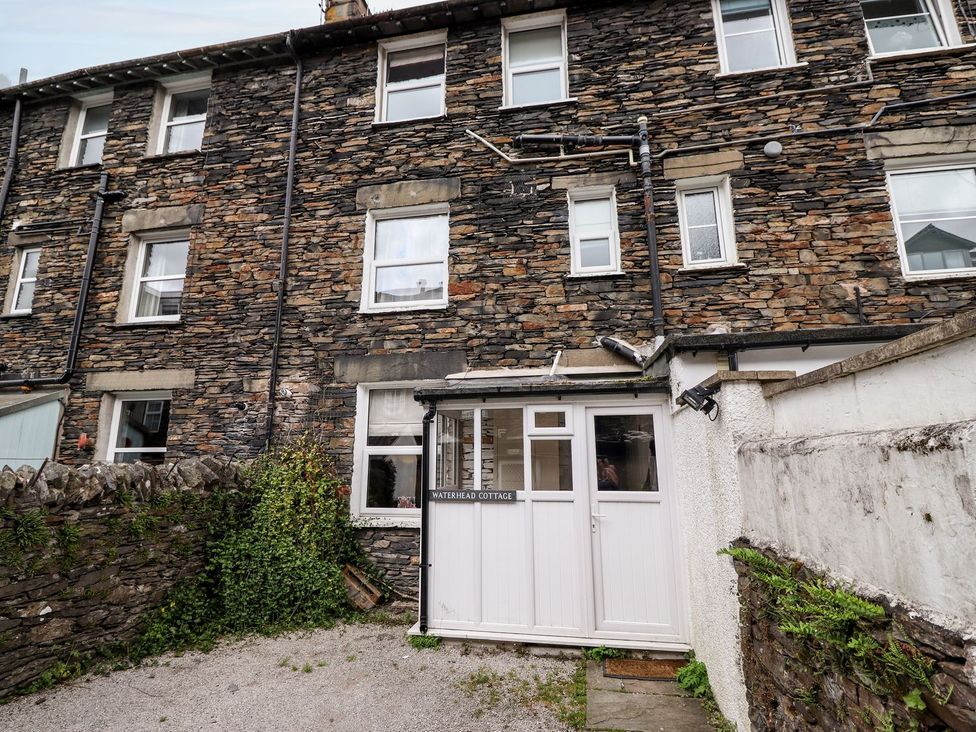 An outdoor view of Waterhead Cottage with stone walls and an entrance in Ambleside