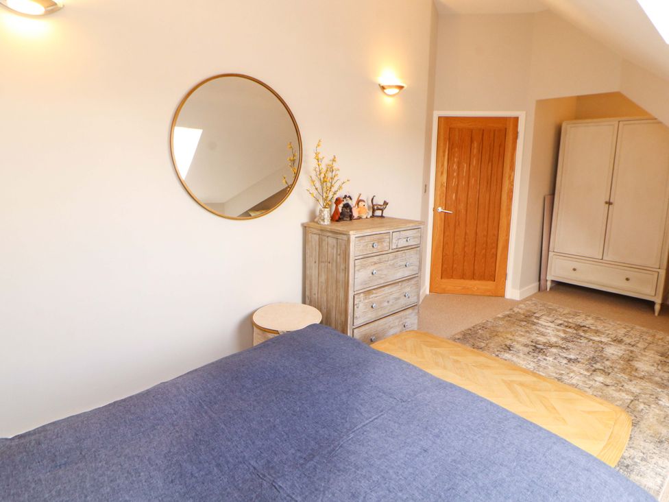 A bedroom with a dresser, mirror, and wardrobe at Lakes View in Keswick