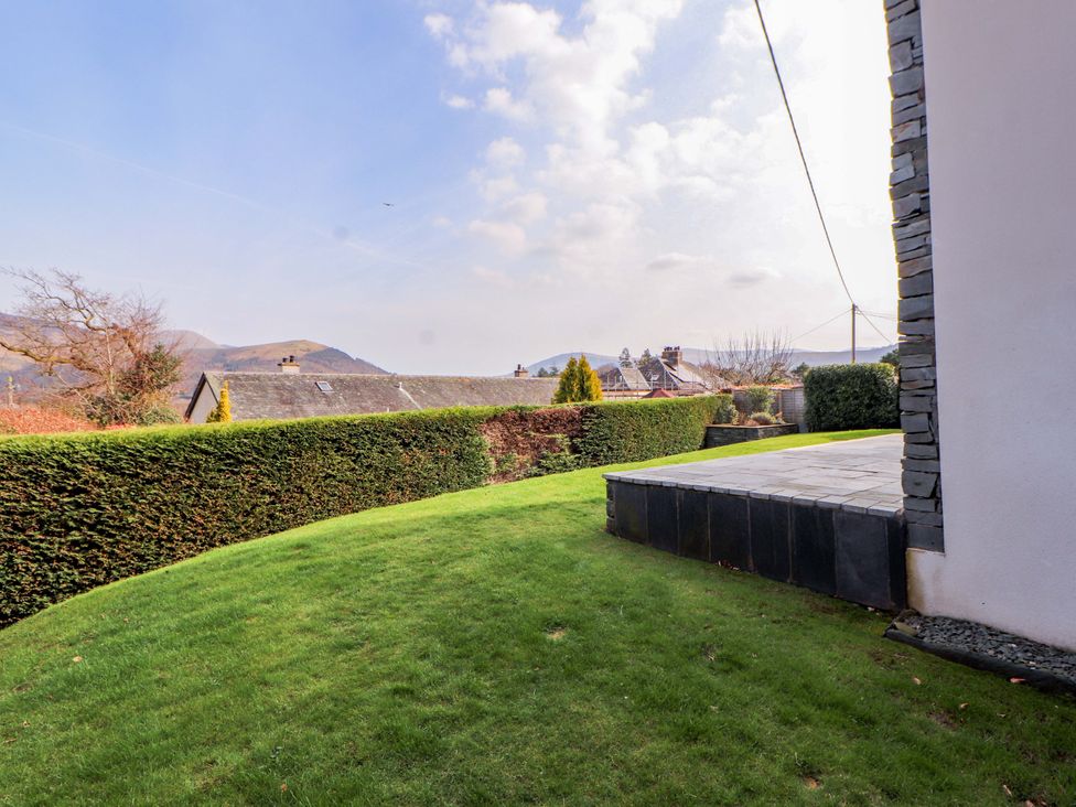 A garden area with grass and slate patio at Lakes View in Keswick