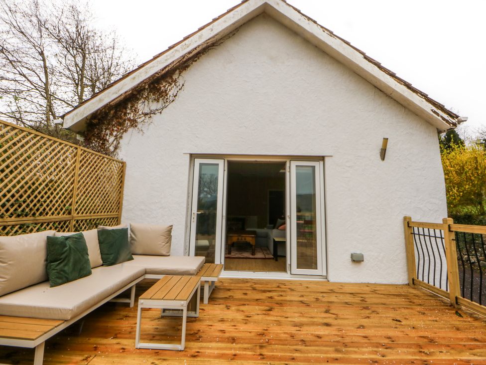 An outdoor deck with a sofa and table at Inglewood Bach in Conwy