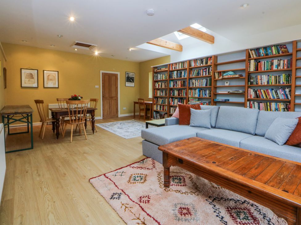 A living room with a sofa and dining area at Inglewood Bach in Conwy