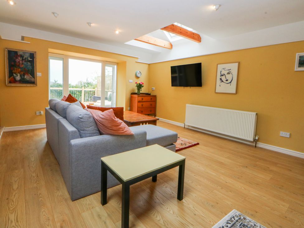 A living room with a sofa, table, and television at Inglewood Bach in Conwy