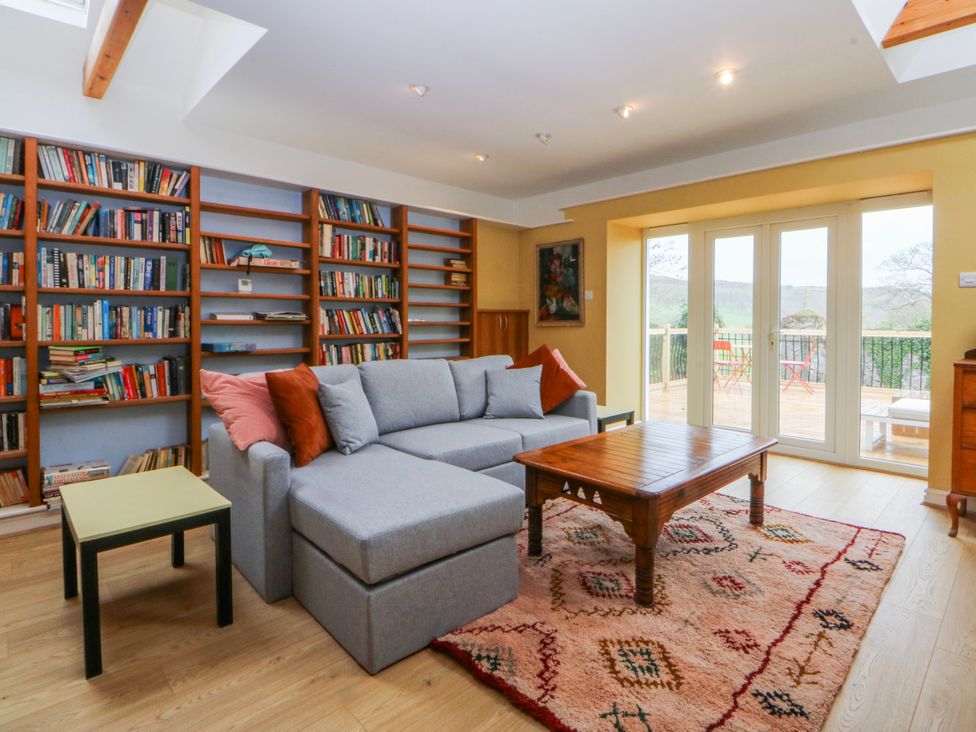 A living room with bookshelves and a sofa at Inglewood Bach Conwy