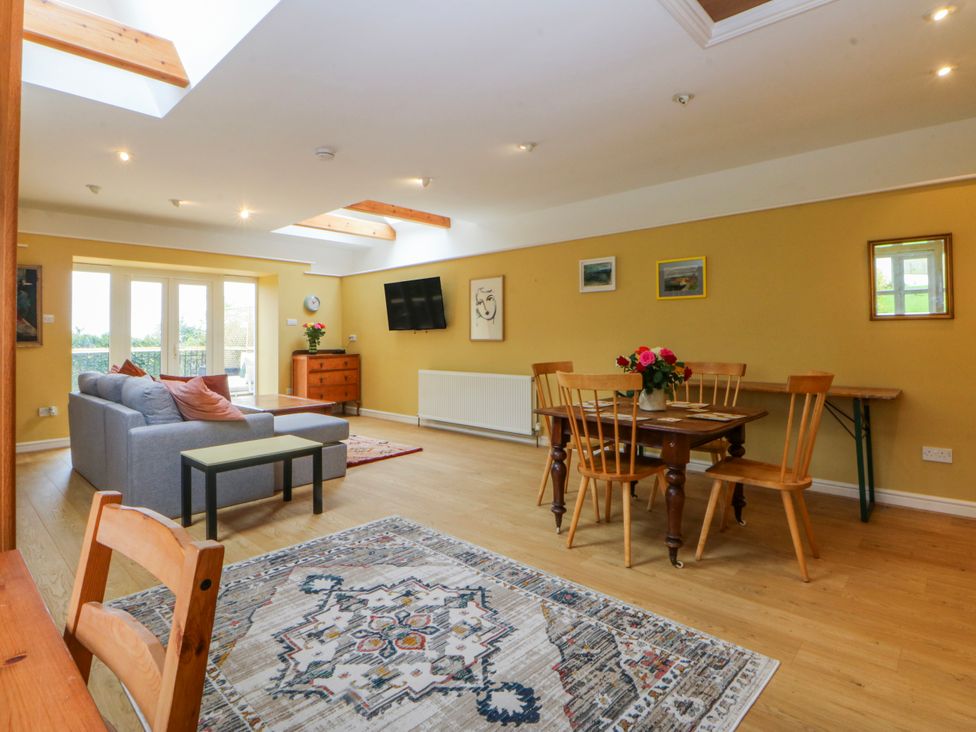 A living room with a sofa, dining table, and television at Inglewood Bach, Conwy