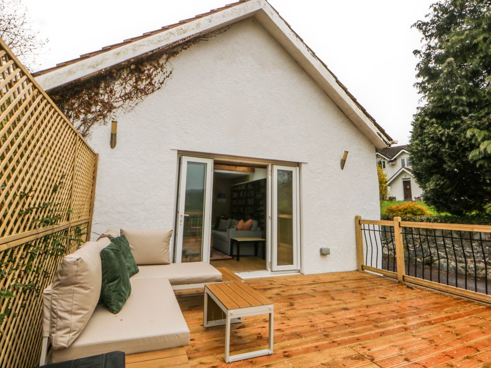 A deck with seating and a table at Inglewood Bach Conwy