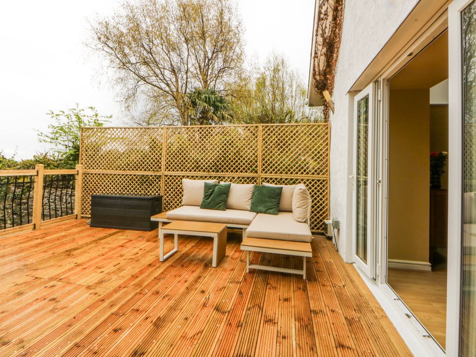 An outdoor seating area with a wooden deck at Inglewood Bach Conwy
