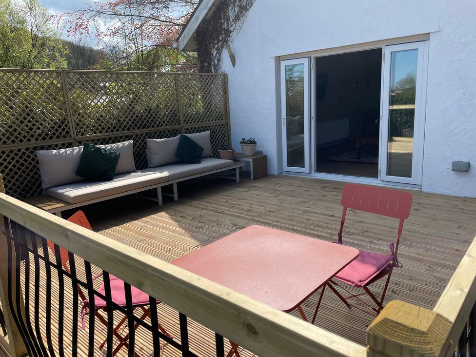An outdoor seating area with a bench and table at Inglewood Bach in Conwy