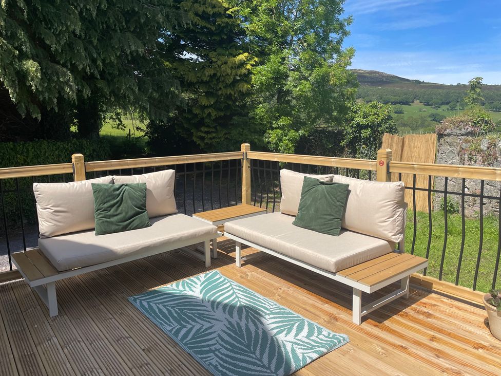 An outdoor seating area with cushions and a rug at Inglewood Bach in Conwy