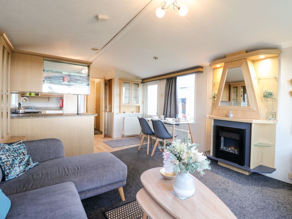 A living room with a sofa, fireplace, and dining area at Granada at Avalon Eco Farm, Cambridge
