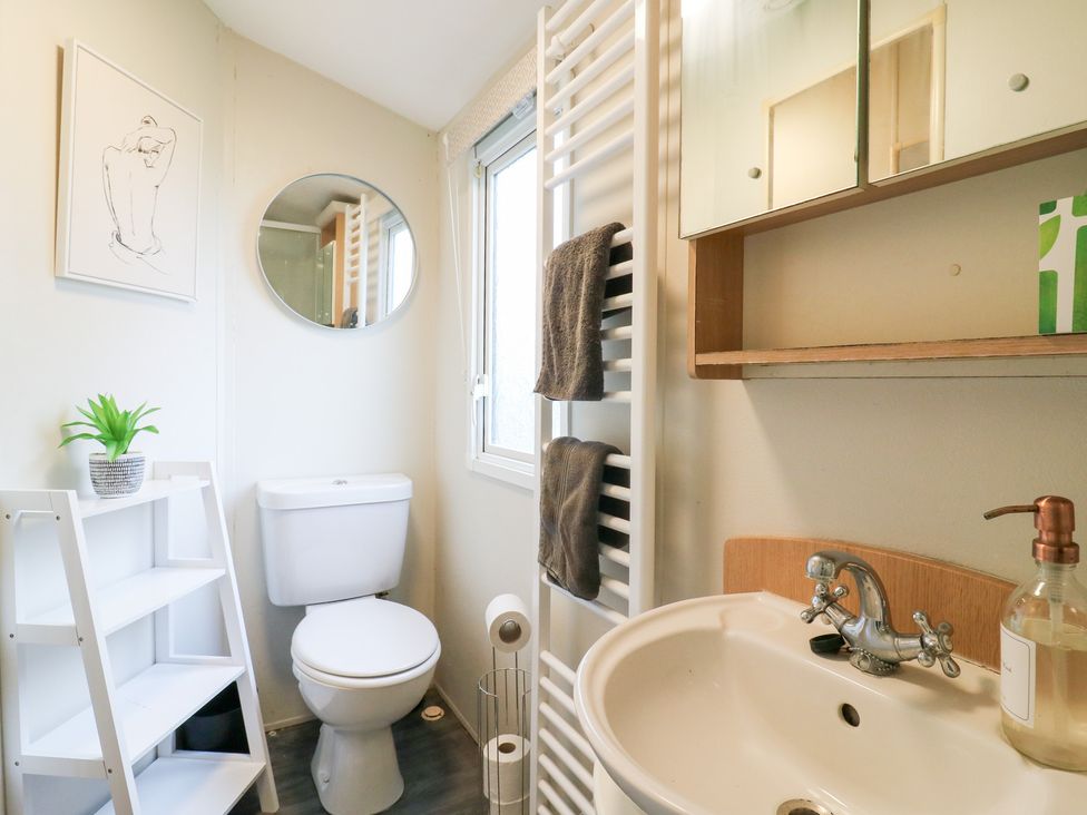 A bathroom with a sink, toilet, mirror, and shelf at Granada at Avalon Eco Farm in Cambridge