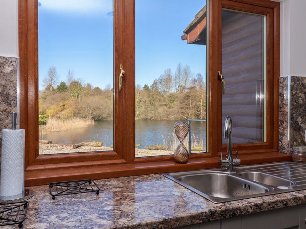 A kitchen sink with a window overlooking a lake at Star Carr Lakes